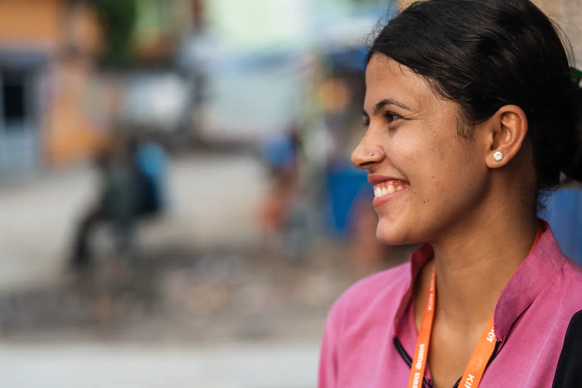 Young woman in a pink shirt smiling, seen in profile