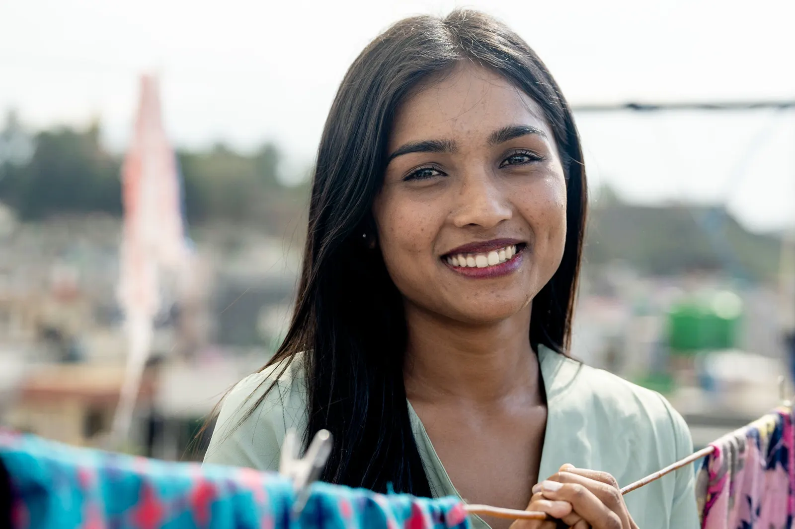Young woman smiling while hanging laundry on a rooftop