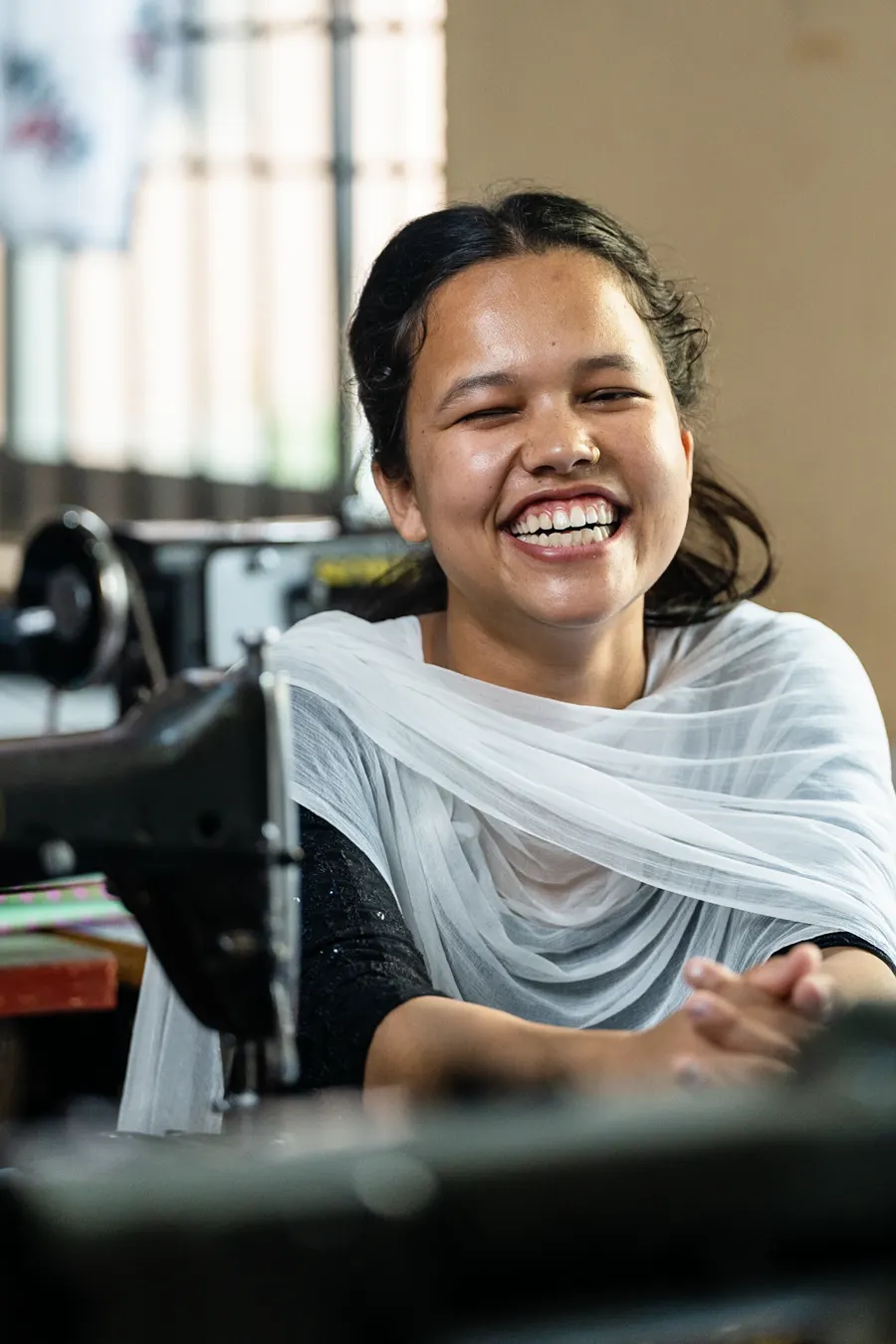 Young woman laughing at a sewing machine during vocational training